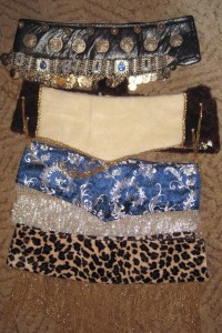 From top: base with coin belt attached, fake fur covered base for reindeer costume, damask-covered belt with silver glass bead fringe, animal pattern Velboa covered base with gold glass bead fringe. All made using the same technique.